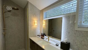 Ein modernes Badezimmer mit Bodendusche, großem Spiegel und Waschtisch mit Handtuchhalter.