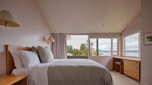 Un dormitorio con cama, mesitas de noche, escritorio y ventana con vistas.