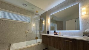 A modern bathroom with a freestanding bathtub, a large mirror, and a vanity with a countertop. - Chalet 5 (Taupo)