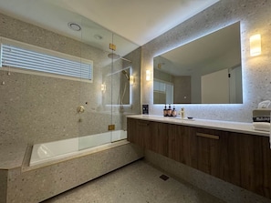 A modern bathroom with a freestanding bathtub, a large mirror, and a vanity with a countertop.