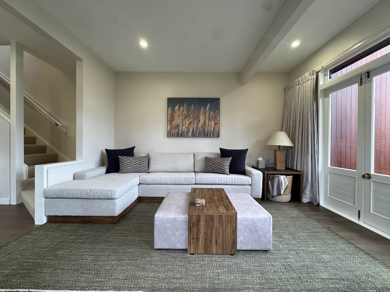 A modern living room with a sectional sofa, a wooden coffee table, and a painting on the wall.