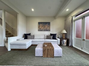 A modern living room with a sectional sofa, a wooden coffee table, and a painting on the wall.
