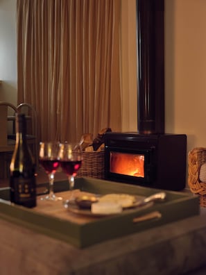 A cozy room with a fireplace, a bottle of wine, and glasses on a tray. - Chalet 4 (Taupo)