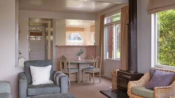 A cozy living room with a fireplace, a dining area, and a kitchen visible through an open door.
