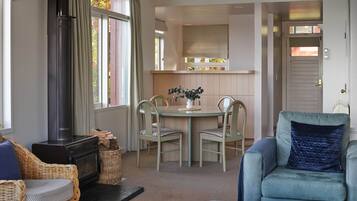 A cozy living room with a fireplace, a dining area with a table and chairs, and a kitchen area with a window.