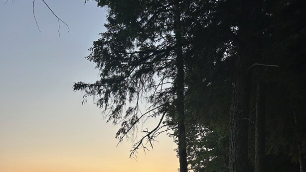 A lakeside view with a wooden bench and chairs, surrounded by trees and a clear sky. - Escape to Green Lake (Ellsworth)