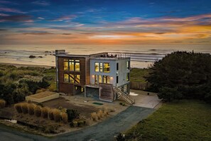 Una casa moderna de dos pisos con un balcón grande con vista al mar.
