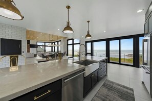 Una cocina moderna con una isla grande, electrodomésticos de acero inoxidable e iluminación colgante.