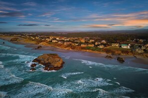 A coastal town with a beach, rocky outcrops, and houses along the shoreline.