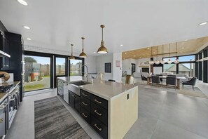 Cozinha moderna com ilha central, armários pretos e iluminação pendente.