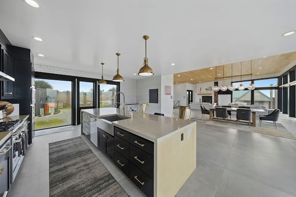 A modern kitchen with a central island, black cabinetry, and pendant lighting.