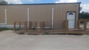 Un edificio con fachada de metal, terraza de madera y puerta con ventanal.