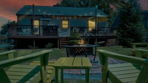 A house with a deck, outdoor seating, and a fire pit.