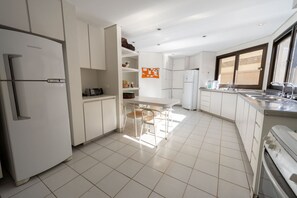 A modern kitchen with white cabinetry, a built-in oven, and a dining area with a table and chairs.