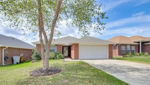 A residential house with a garage, brick exterior, and a lawn with a tree. - 3 Mi to Escambia Bay: Home w/ Deck & Private Yard! (Milton)