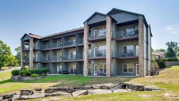 A multi-story building with balconies, outdoor seating, and a landscaped area.