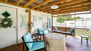 Eine überdachte Veranda mit Holzbalken, einer Bank, Stühlen und einem Tisch.