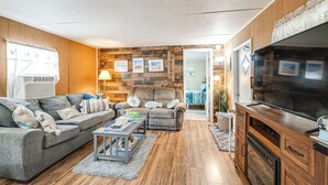 Ein modernes Wohnzimmer mit einem grauen Sofa, einer Holzvertäfelung an der Wand und einem großen Flachbildfernseher.