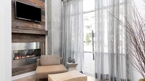 Una sala de estar moderna con chimenea, un sofá, una mesa de centro y cortinas translúcidas.