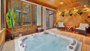 Une cabane en bois avec un jacuzzi, des meubles en osier et des plantes en pot.