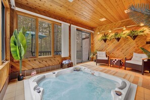 Une cabane en bois avec un jacuzzi, des meubles en osier et des plantes en pot.