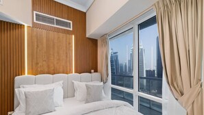 Una camera d'albergo moderna con un letto grande, pannelli in legno, vista sulla città e una finestra con tende.