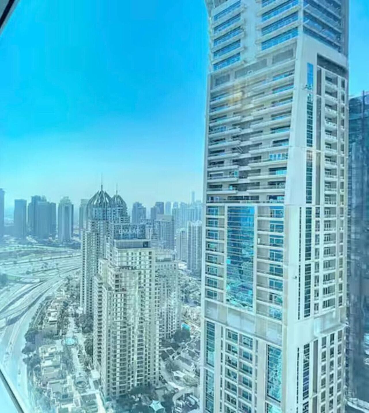 Een hoog gebouw met een modern architectonisch ontwerp, meerdere etages met grote ramen en een opvallende centrale spits.