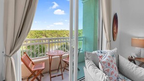 A balcony with a table and chairs, a sofa, and a view of greenery.