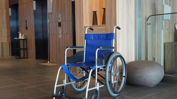 A wheelchair in a modern lobby with a tiled floor and a glass partition.