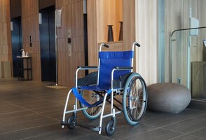 Una silla de ruedas en un vestíbulo moderno con suelo de baldosas y un panel de vidrio.