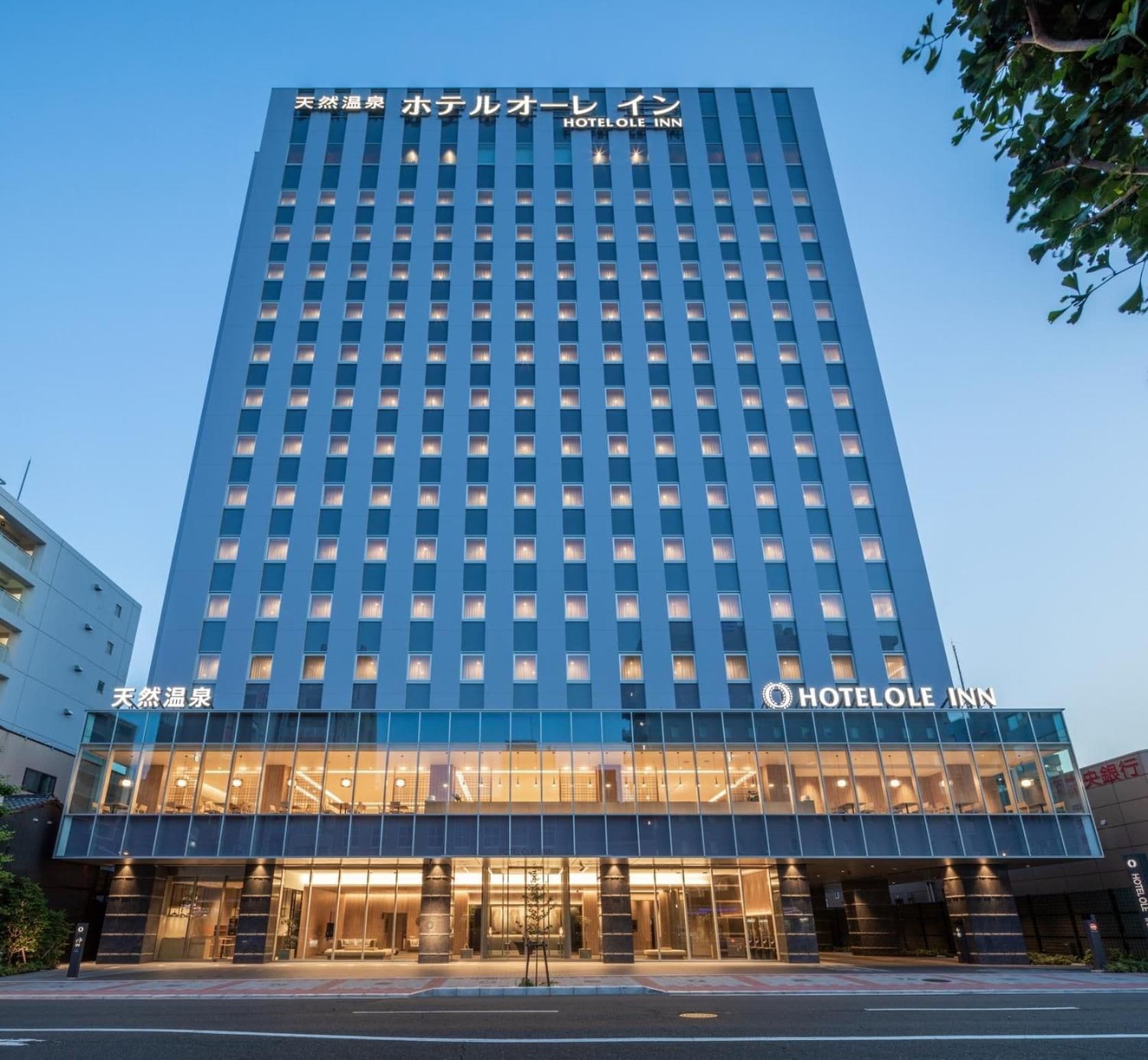 A hotel with a modern facade, multiple floors, and a prominent entrance with glass doors.