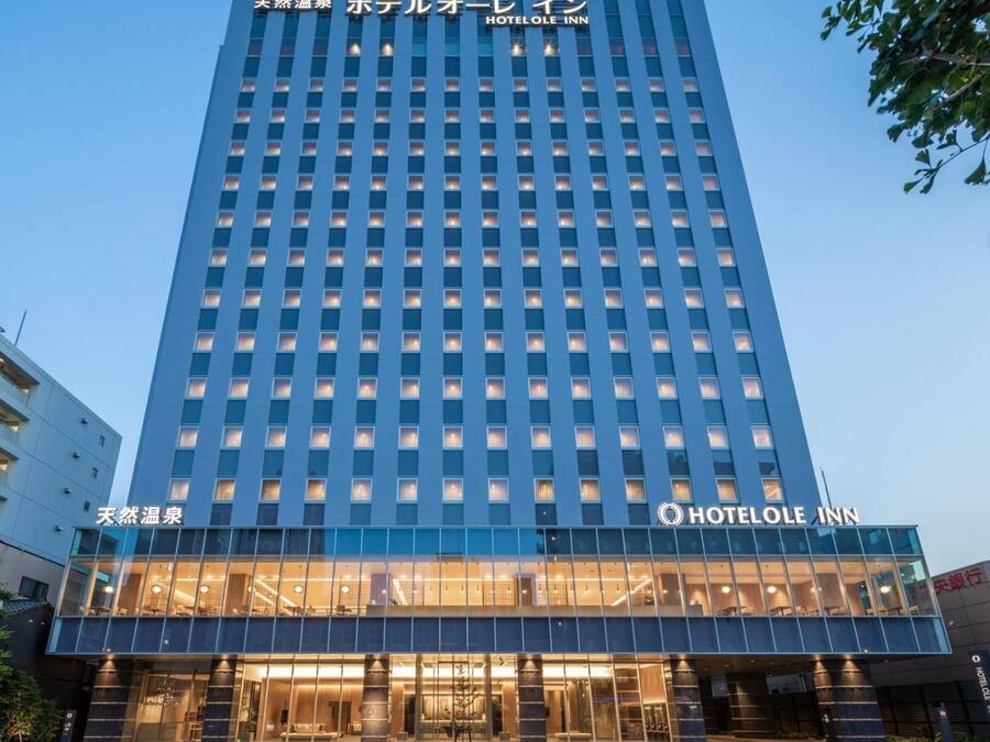 A hotel with a modern facade, multiple floors, and a prominent entrance with glass doors.
