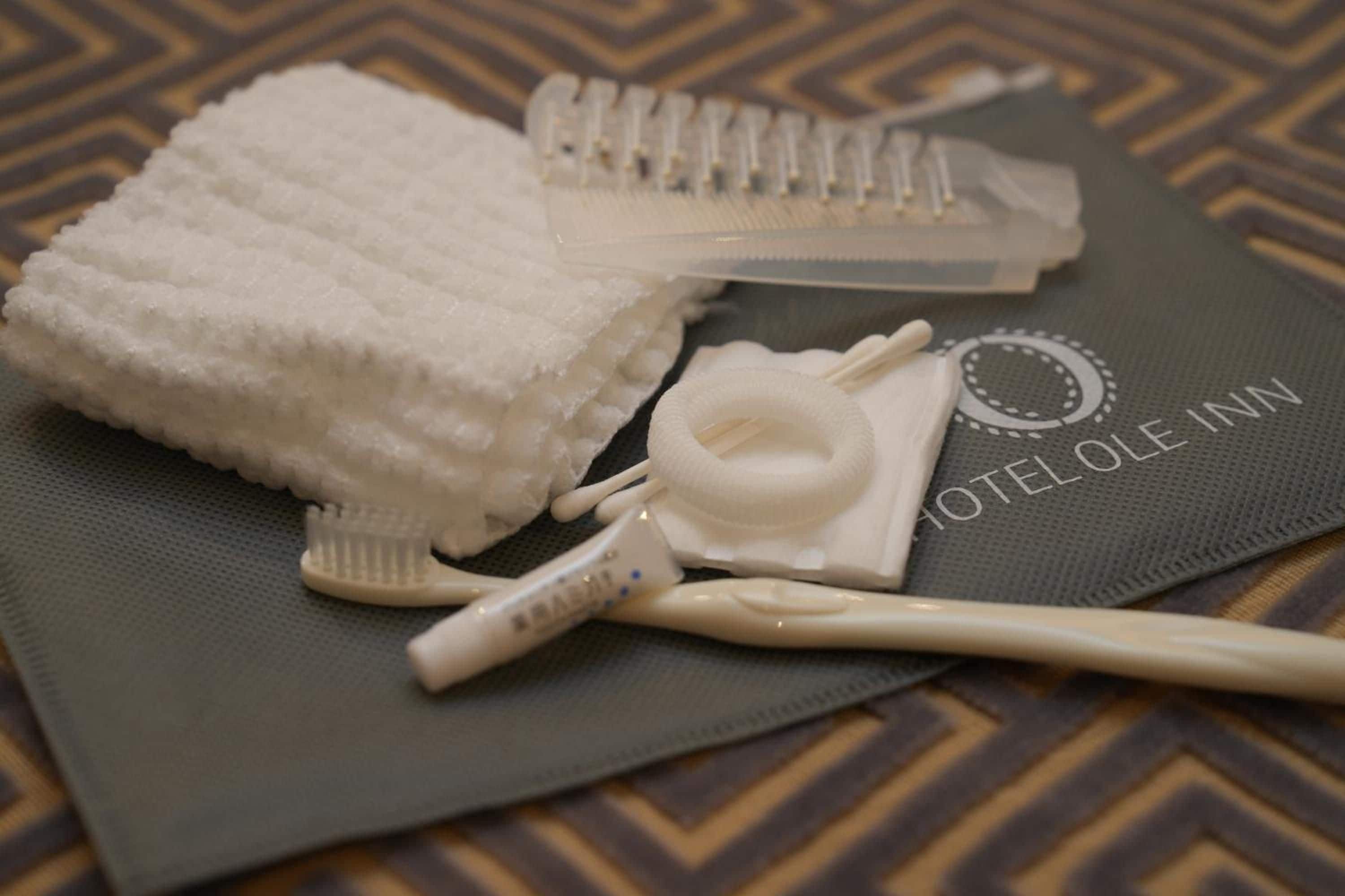 A set of toiletries including a toothbrush, toothpaste, and a towel on a hotel bed.