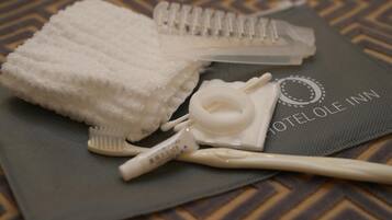 A set of toiletries including a toothbrush, toothpaste, and a towel on a hotel bed.