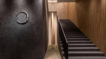 Un interior moderno con una escalera, paredes oscuras y un suelo con textura.