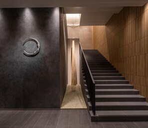 A modern interior with a staircase, dark walls, and a textured floor. - Hotel Ole Inn (Shizuoka)
