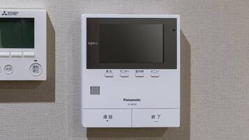 Two electronic devices, one labeled 'Mitsubishi Electric' and the other 'Panasonic,' mounted on a textured wall.
