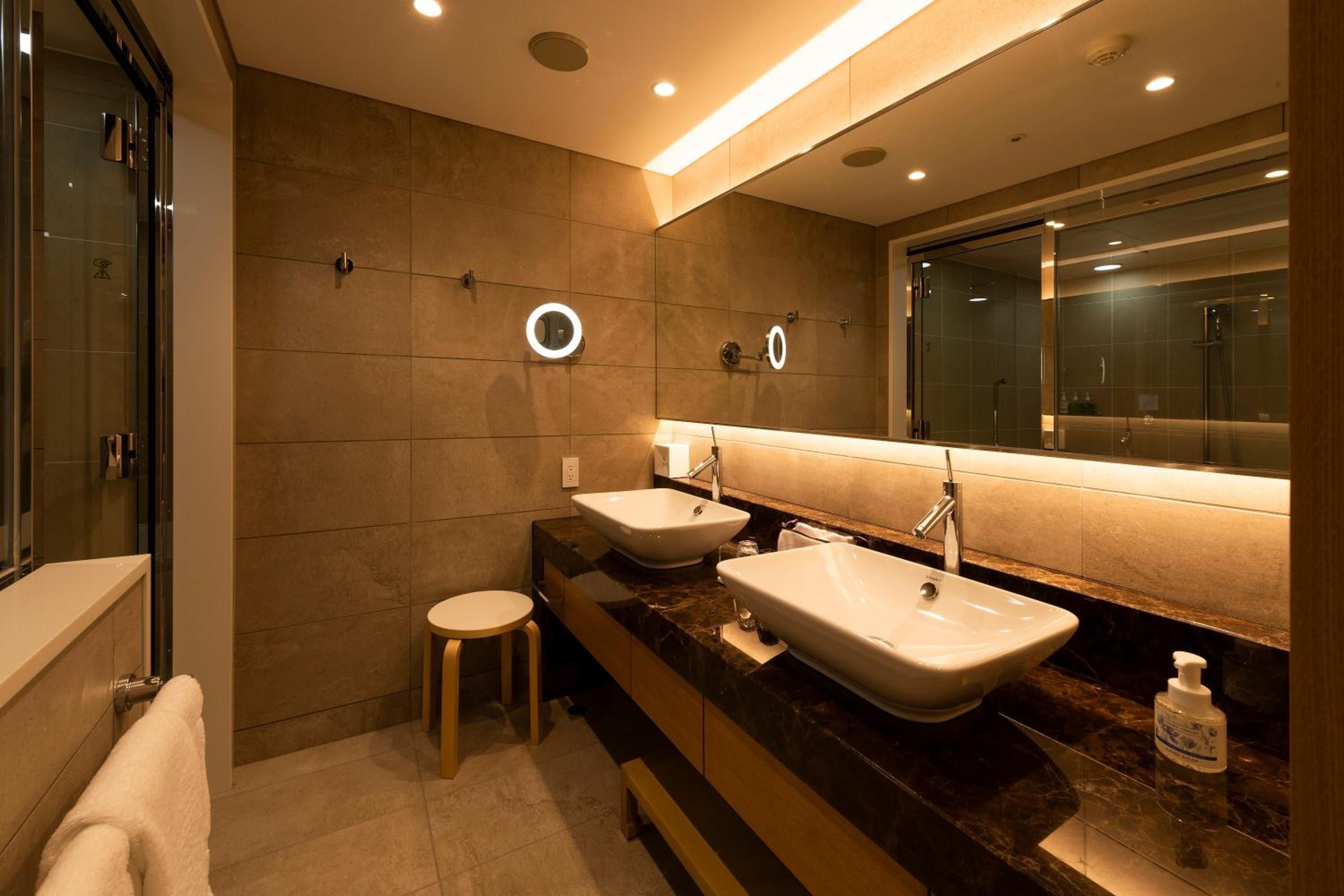 A modern bathroom with two sinks, a mirror, and a shower.