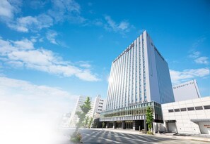 A modern hotel building with a prominent entrance and a clear sky. - Hotel Ole Inn (Shizuoka)