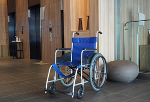 A wheelchair in a modern lobby with a tiled floor and a glass partition.