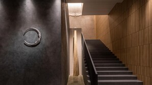 A modern interior with a staircase, dark walls, and a textured floor. - Hotel Ole Inn (Shizuoka)