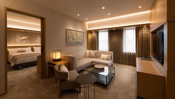 A hotel room with a bed, a sofa, a coffee table, a TV, and a painting on the wall.