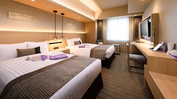 A hotel room with two beds, a desk with a TV, and a window with curtains.