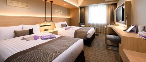 A hotel room with two beds, a desk with a TV, and a window with curtains.