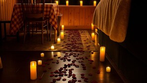 A dimly lit room with a wooden floor, a bed with a blanket, a neon sign reading "Happily Ever After", and a table with a checkered tablecloth. - Rustic Log Cabin near National Park with Hot Tub & Mountain Views (Allenspark)