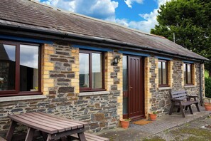 A stone building with a dark brown door, windows, and a bench outside. - The Stable, Aberystwyth (Aberystwyth)