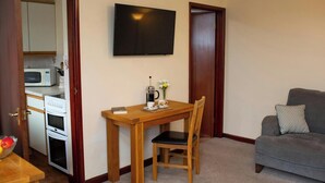 A compact living space with a kitchenette, a dining table, a single chair, and a grey sofa. - The Stable, Aberystwyth (Aberystwyth)