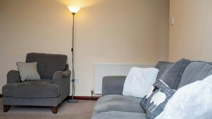 A living room with a grey sofa, a grey armchair, a floor lamp, and a radiator. - The Stable, Aberystwyth (Aberystwyth)