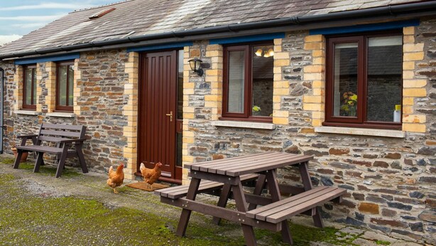 A stone building with a wooden door, windows, and a picnic table.