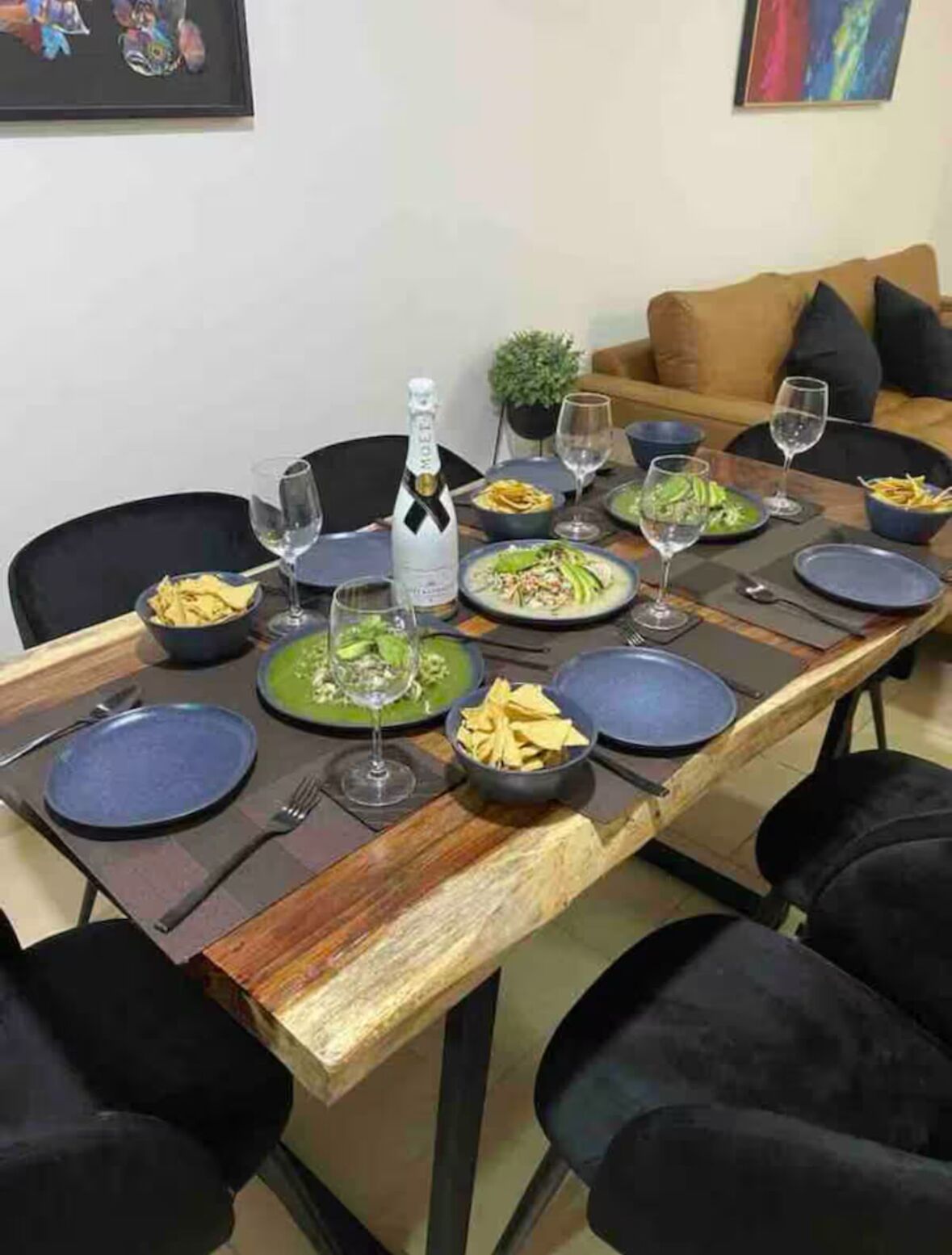 A dining table set with plates, glasses, and a bottle of champagne.